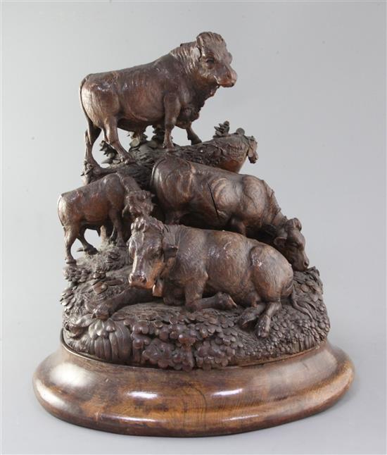 A late 19th century Black Forest carved wood group of a bull, two cows and a calf upon a mountain side, height 14in.
